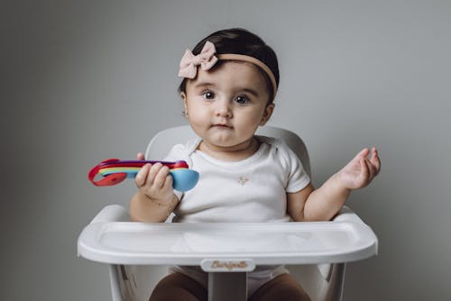 A baby sitting in a high chair with a toy