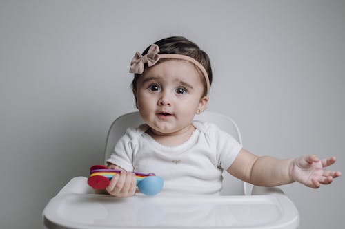 Free A baby sitting in a high chair with a toy Stock Photo