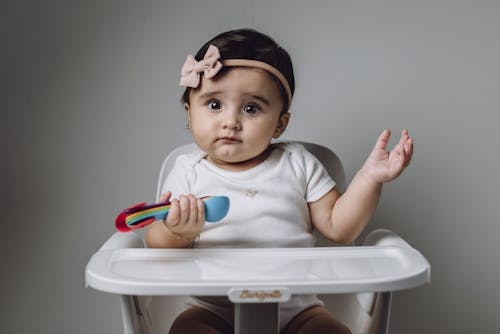 Free A baby sitting in a high chair with a toy Stock Photo