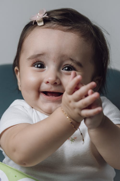 A baby girl is smiling and clapping her hands