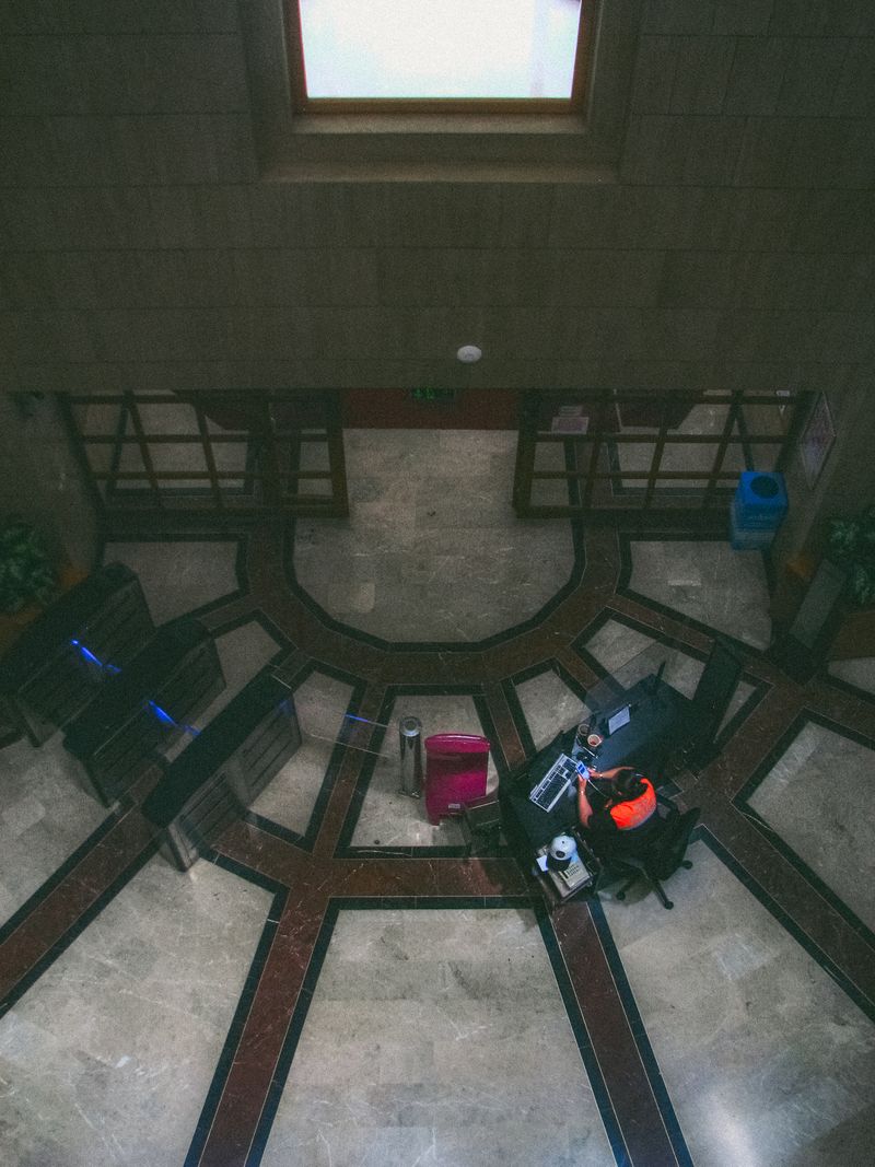 High-angle view of a security guard at an empty office lobby desk, emphasizing structure and design.