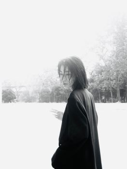 A mysterious black and white portrait of a woman outdoors in winter attire.