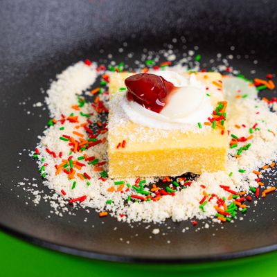 Cake square with cream, cherry and rainbow sprinkles on a black plate. Photo by Ali Dashti on Pexels.