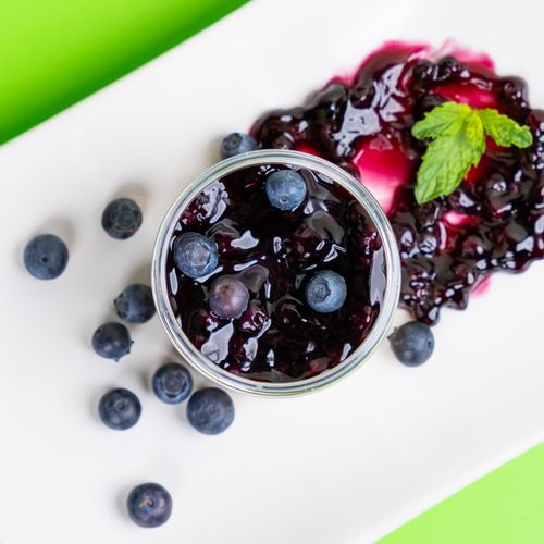 Free Top view of fresh blueberry jam with whole berries and mint on a white plate. Stock Photo
