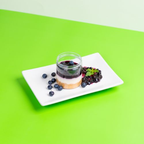 Free Blueberry dessert in a glass jar with mint garnish on a vibrant green background. Stock Photo
