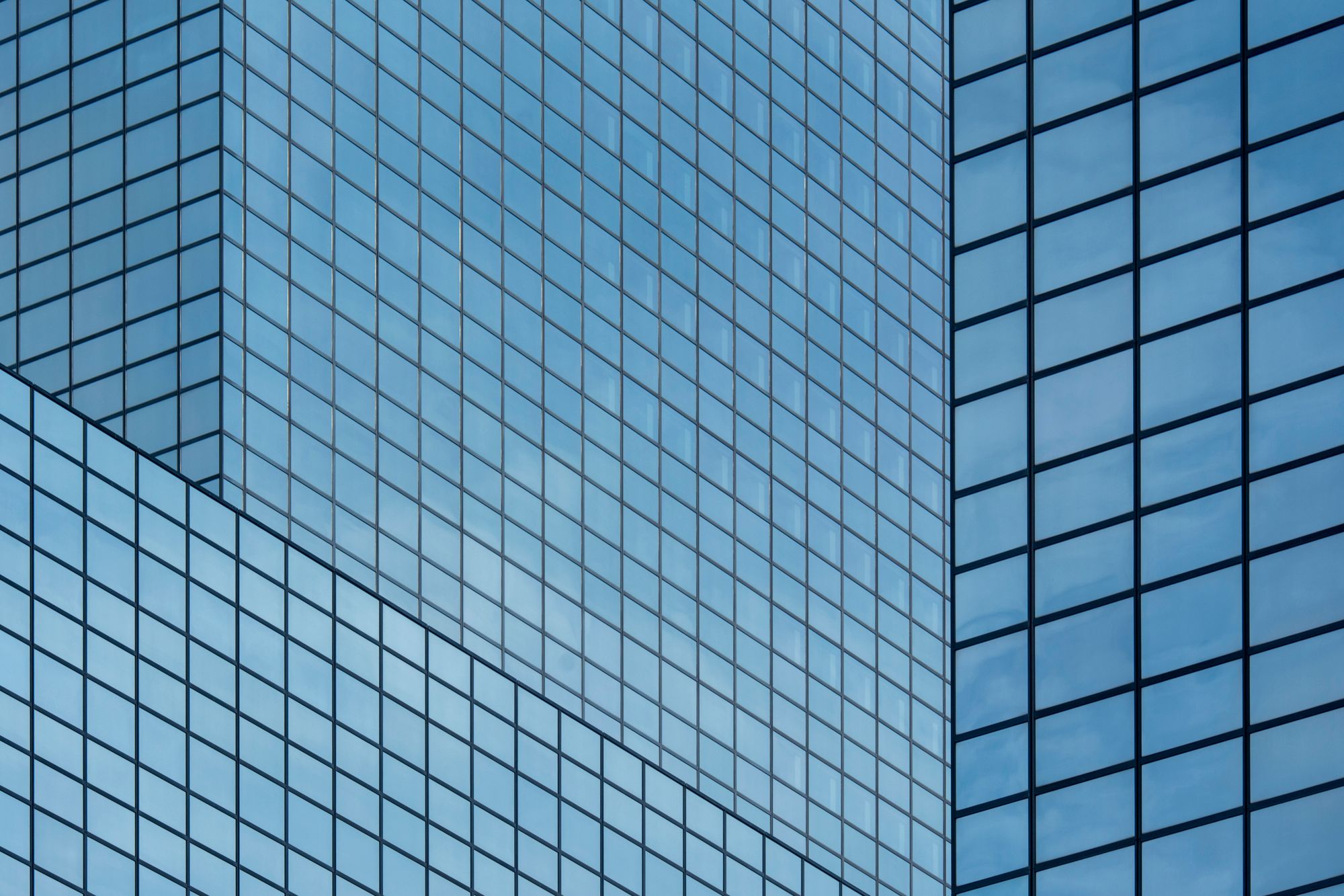 A blue glass facade with a repeating geometric pattern