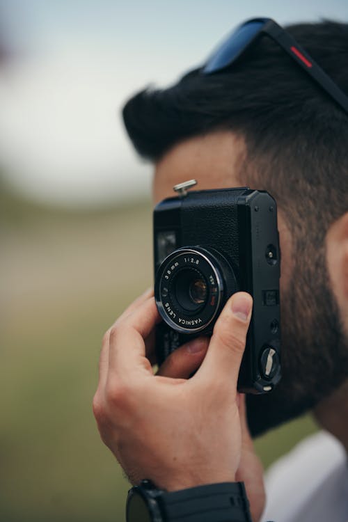 Close-up of a Man Taking Pictures with a Vintage 35mm Film Camera