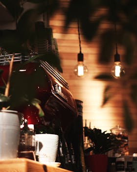 Warmly lit cafe interior featuring a professional espresso machine and hanging light bulbs.