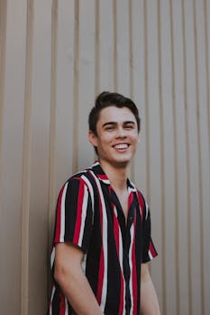 一位穿着时尚条纹衬衫、靠在墙上微笑的男人的肖像