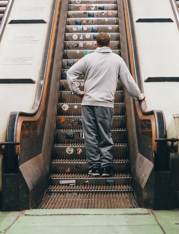 Back View Photo of Man Standing on Escalator