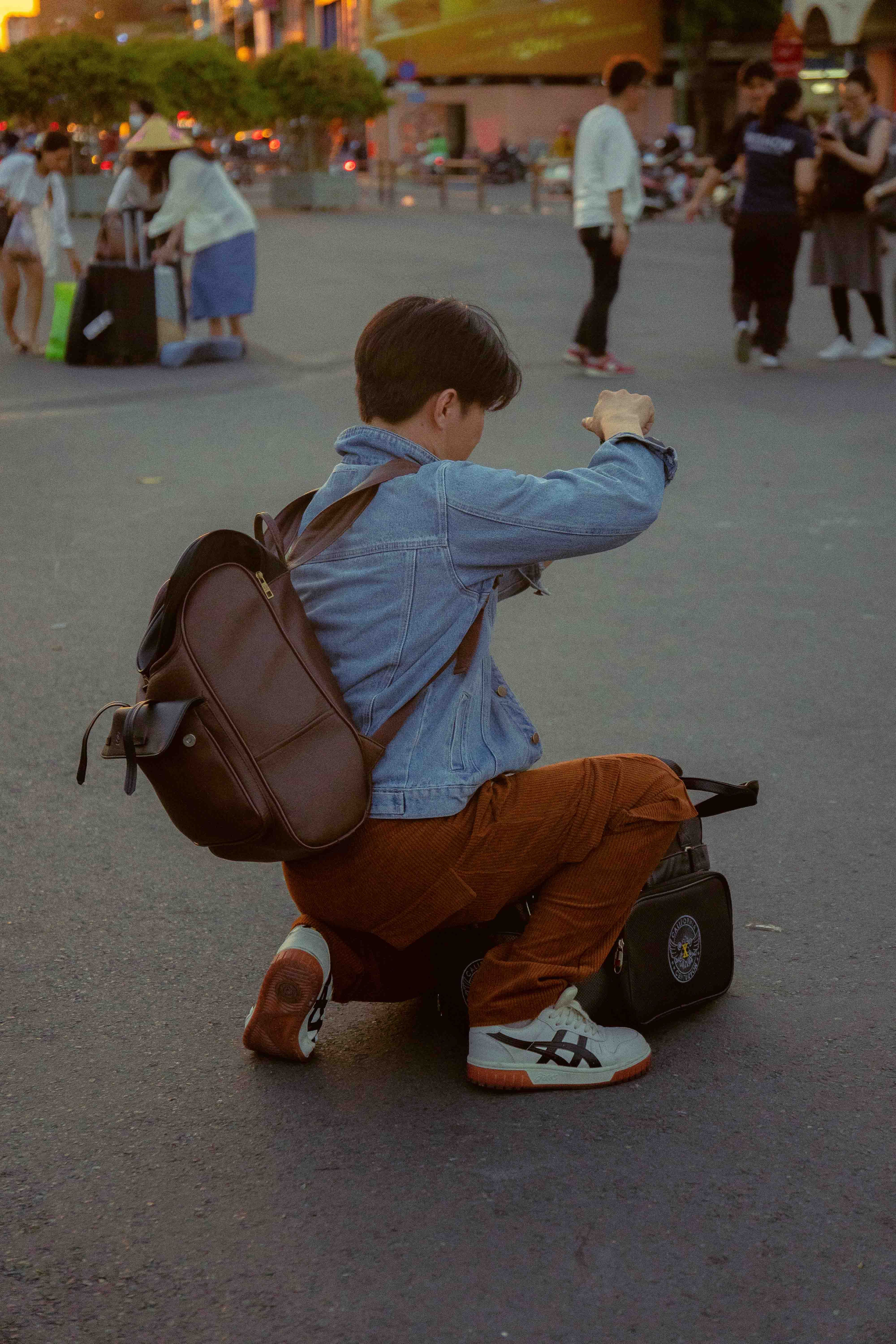 A young photographer kneels in the street to take a picture, capturing urban life in Ho Chi Minh City, Vietnam.