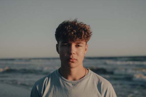 A young man standing on the beach in front of the ocean