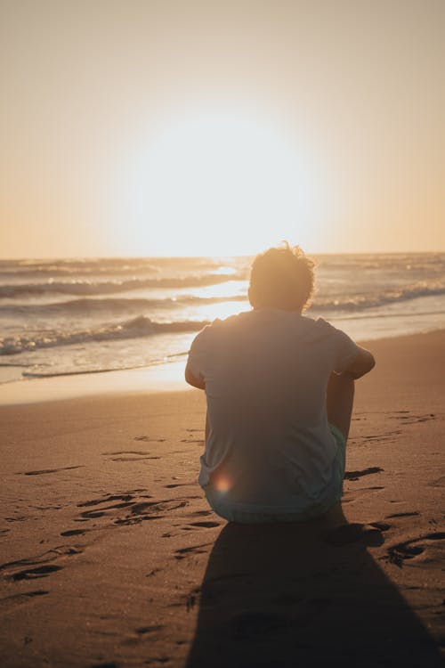 A man sitting on the beach at sunset