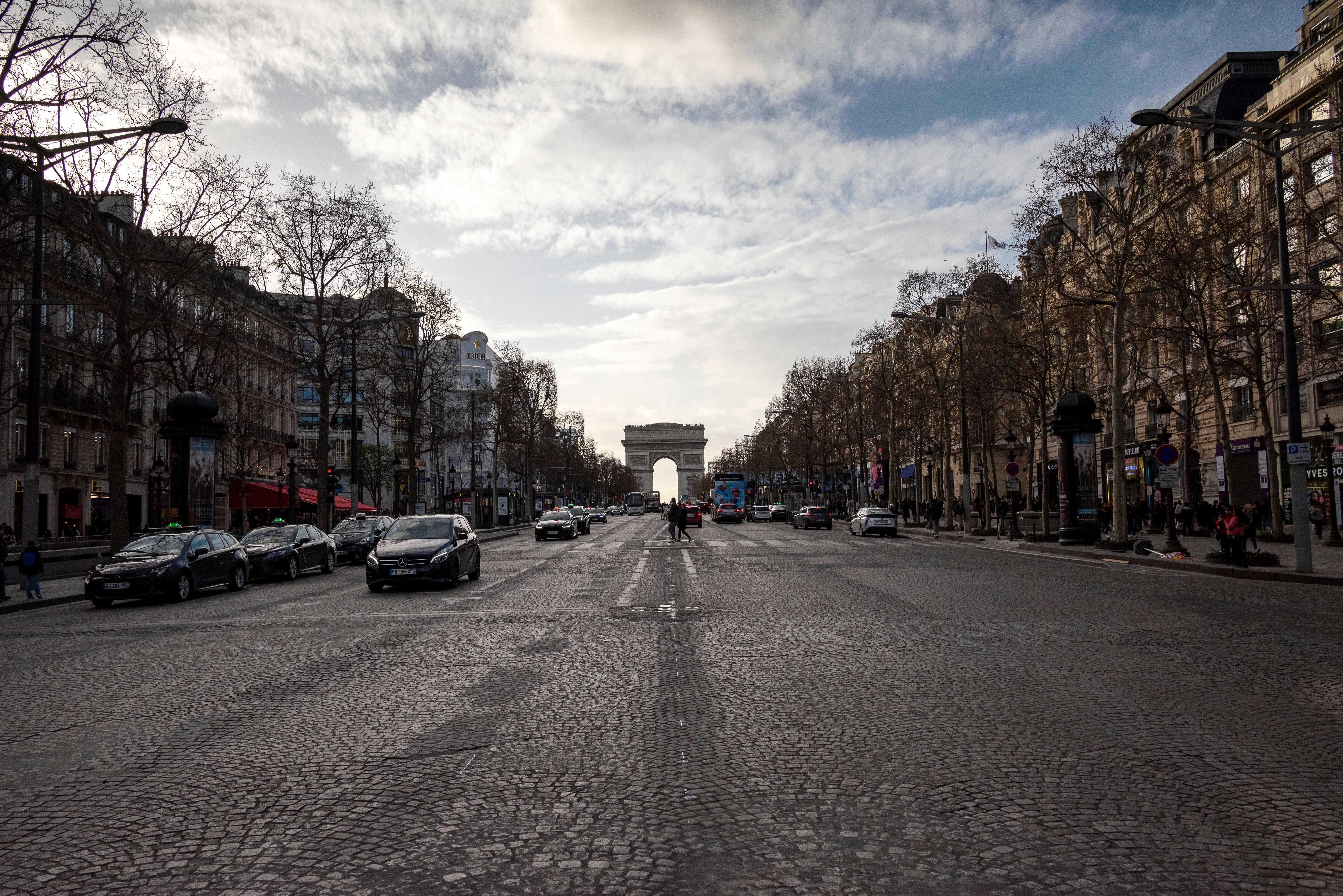 An urban street view of the Champs-Élysées leading up to the iconic Arc de Triomphe in Paris, France. — Notre équipe locale Mister Concierge en intervention à Paris 9e