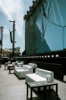 Modern outdoor setup with white sofas and a large stage, perfect for entertainment events.