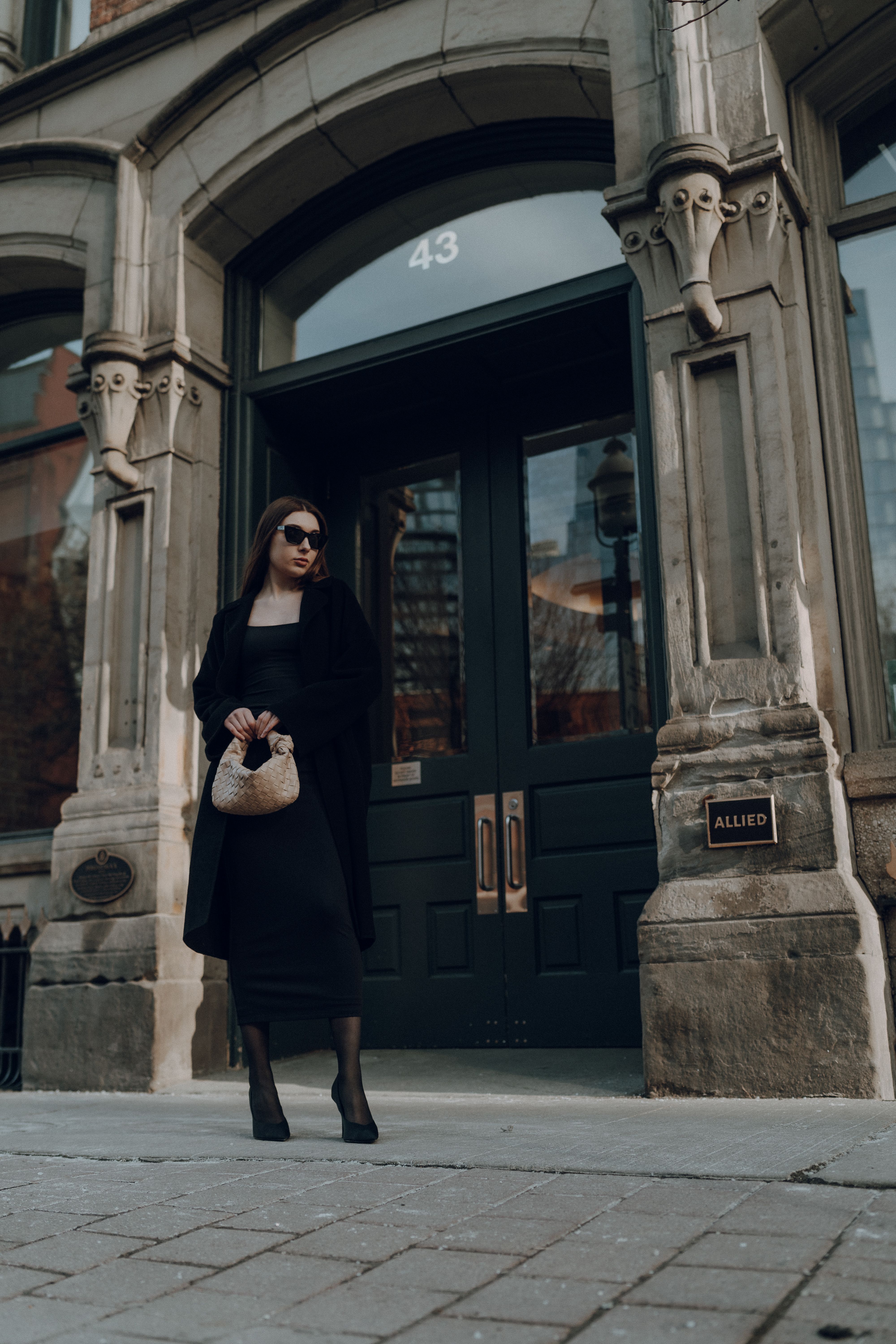 A woman in a black coat and black boots standing on the sidewalk · Free ...