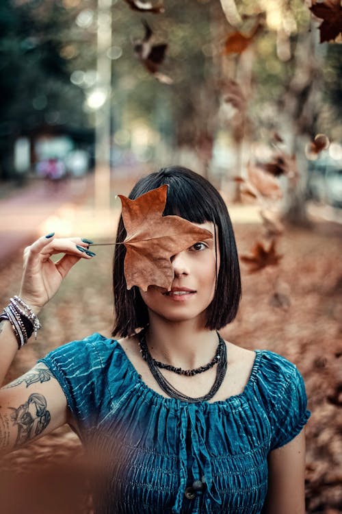 Photo Of Woman Holding Dry Maple Leaf