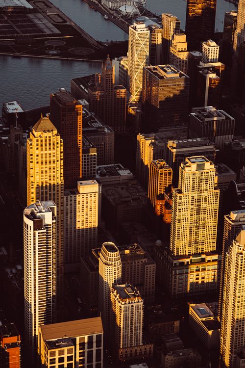 Free Stunning aerial view of a cityscape with skyscrapers illuminated by golden sunset light, capturing urban elegance. Stock Photo