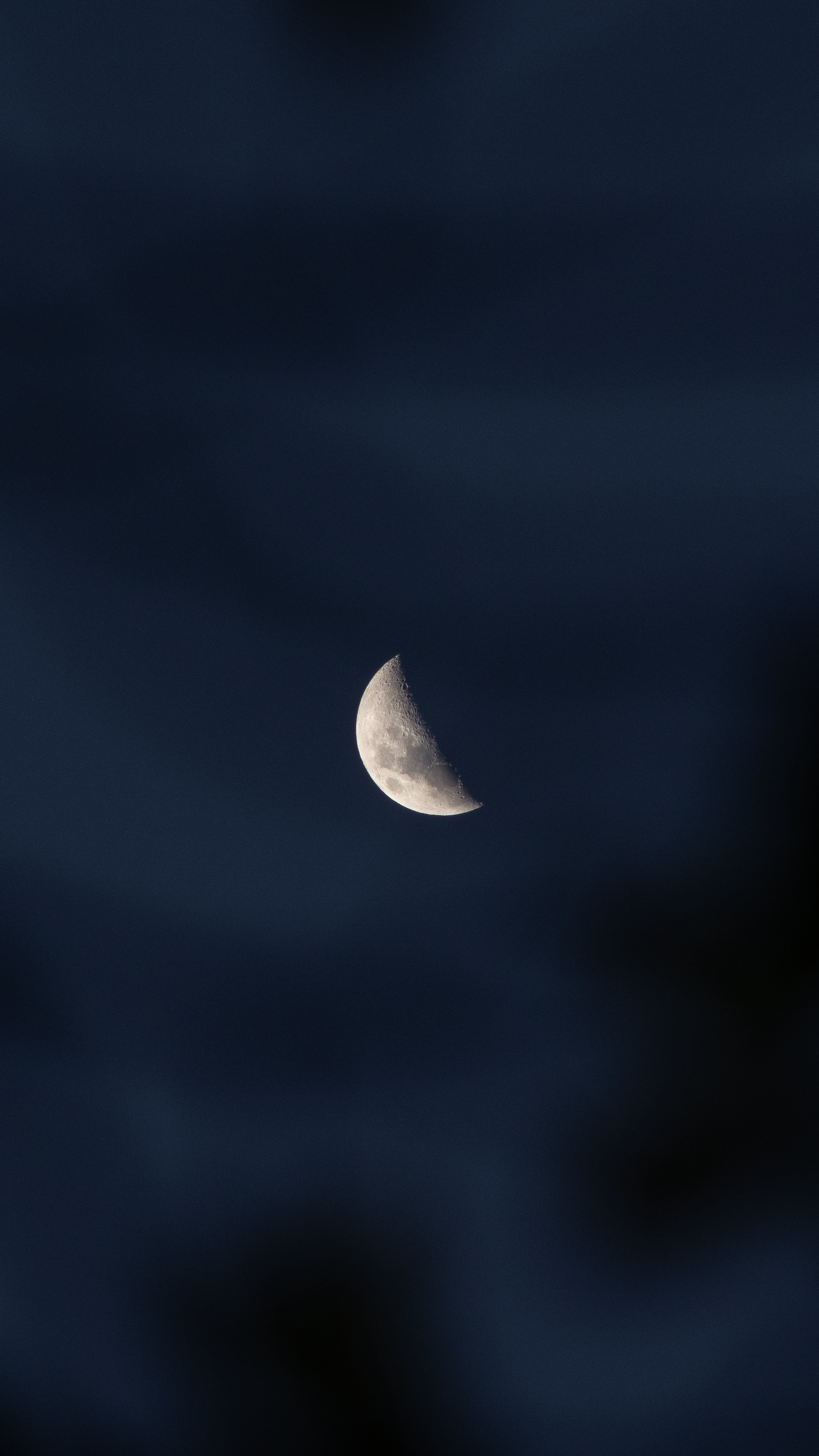 A striking crescent moon amidst dark clouds, captured in a serene night sky.