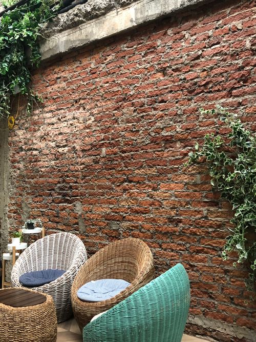 Free Cozy outdoor seating with wicker chairs and ivy climbing a brick wall. Stock Photo