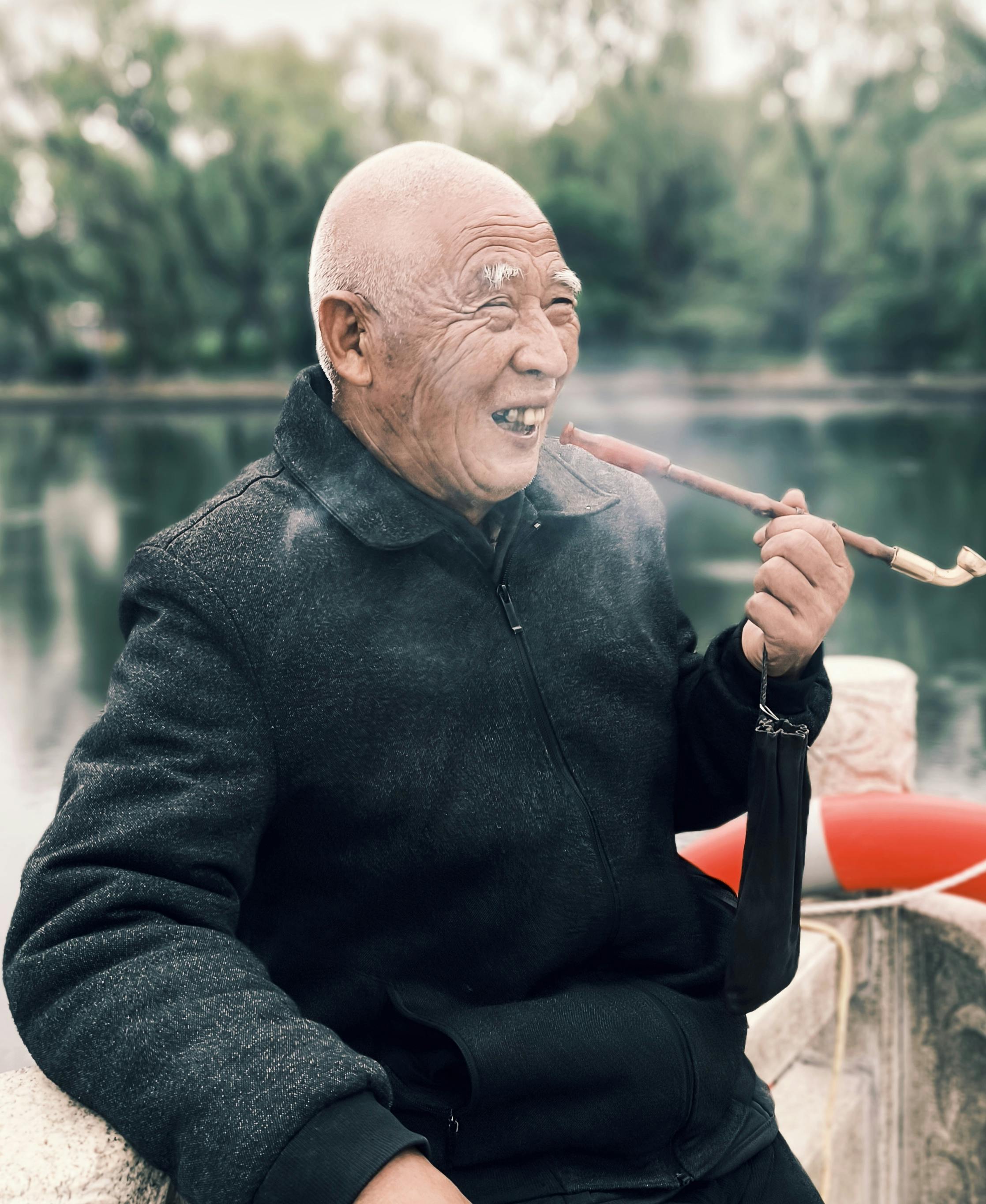 elderly man enjoying a pipe by the lake