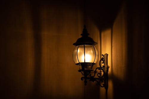 Photo of a Lighted Sconce Mounted on a Brown Wall 