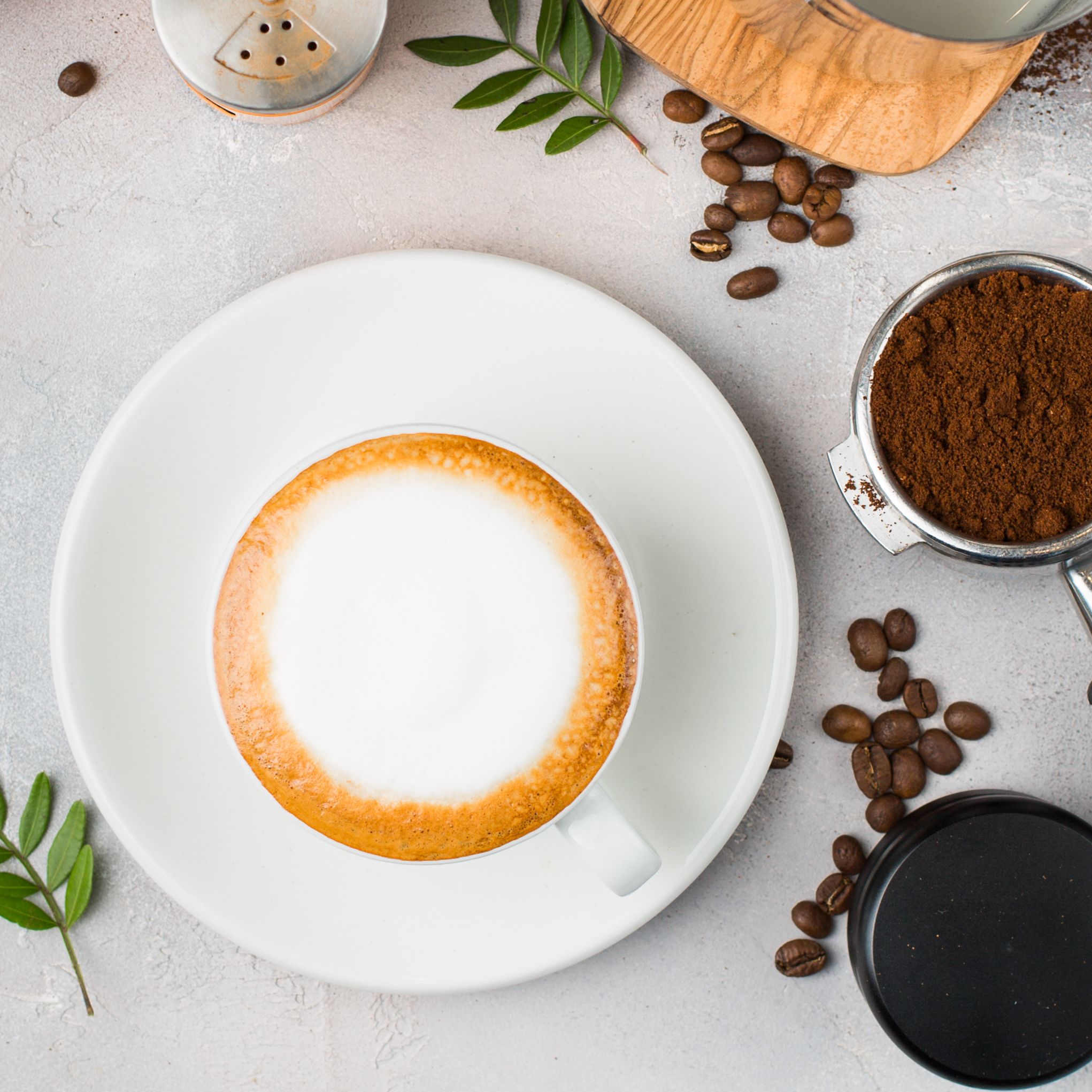 Flat lay of cappuccino, beans and a grinder — photo by Anna Tukhfatullina on Pexels