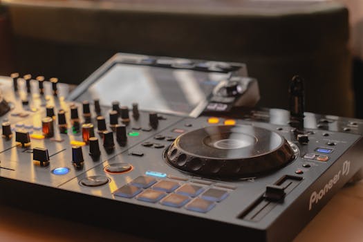 Close-up view of a modern DJ mixer with knobs, sliders, and lights, ideal for music production.