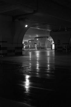 Explore the eerie ambiance of a dimly lit, empty underground tunnel in black and white, evoking mystery.