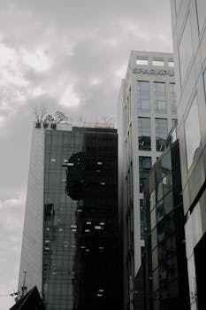 A low-angle shot of modern office buildings in an urban setting under a cloudy sky.