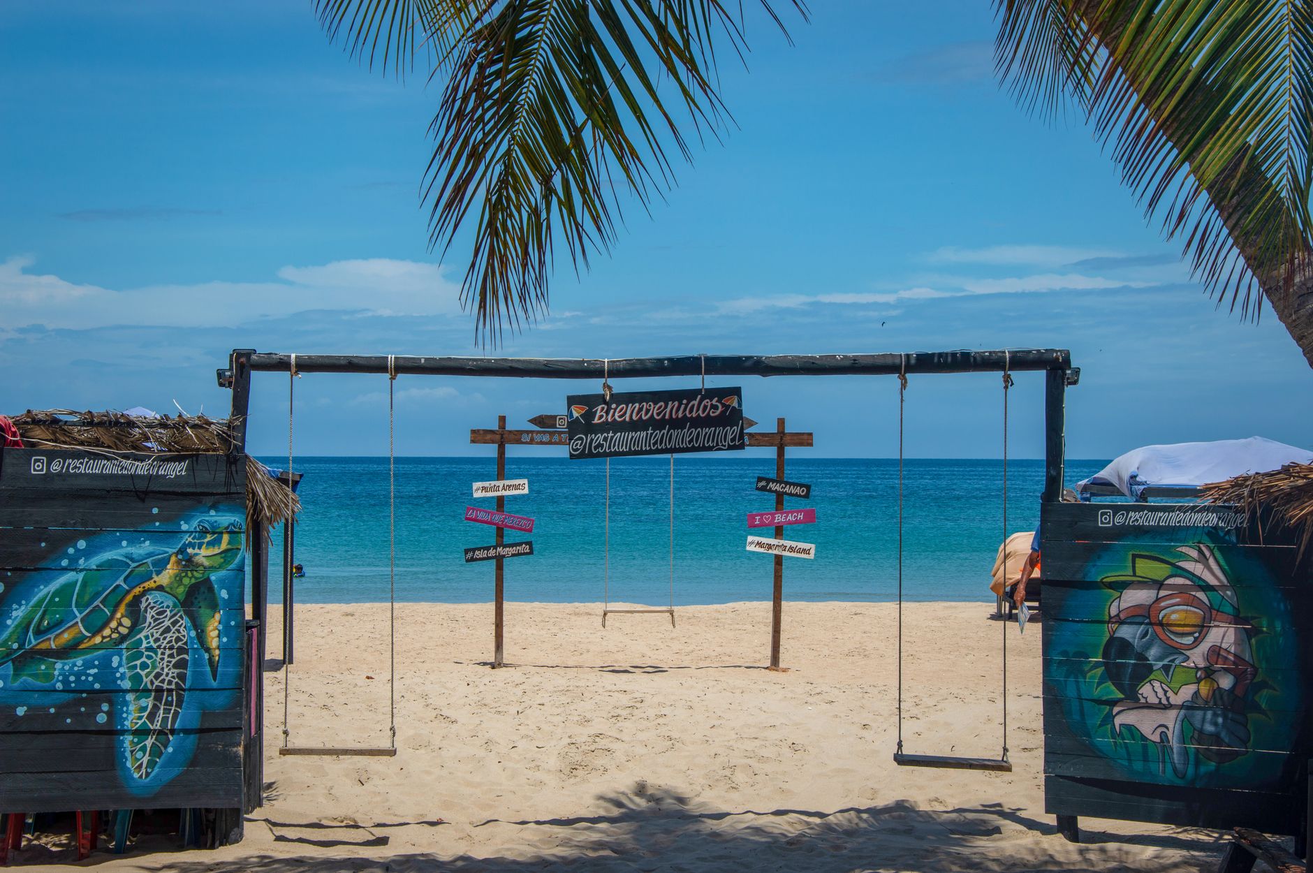 Relaxing beach scene with swings facing the ocean, ideal for travel and leisure.