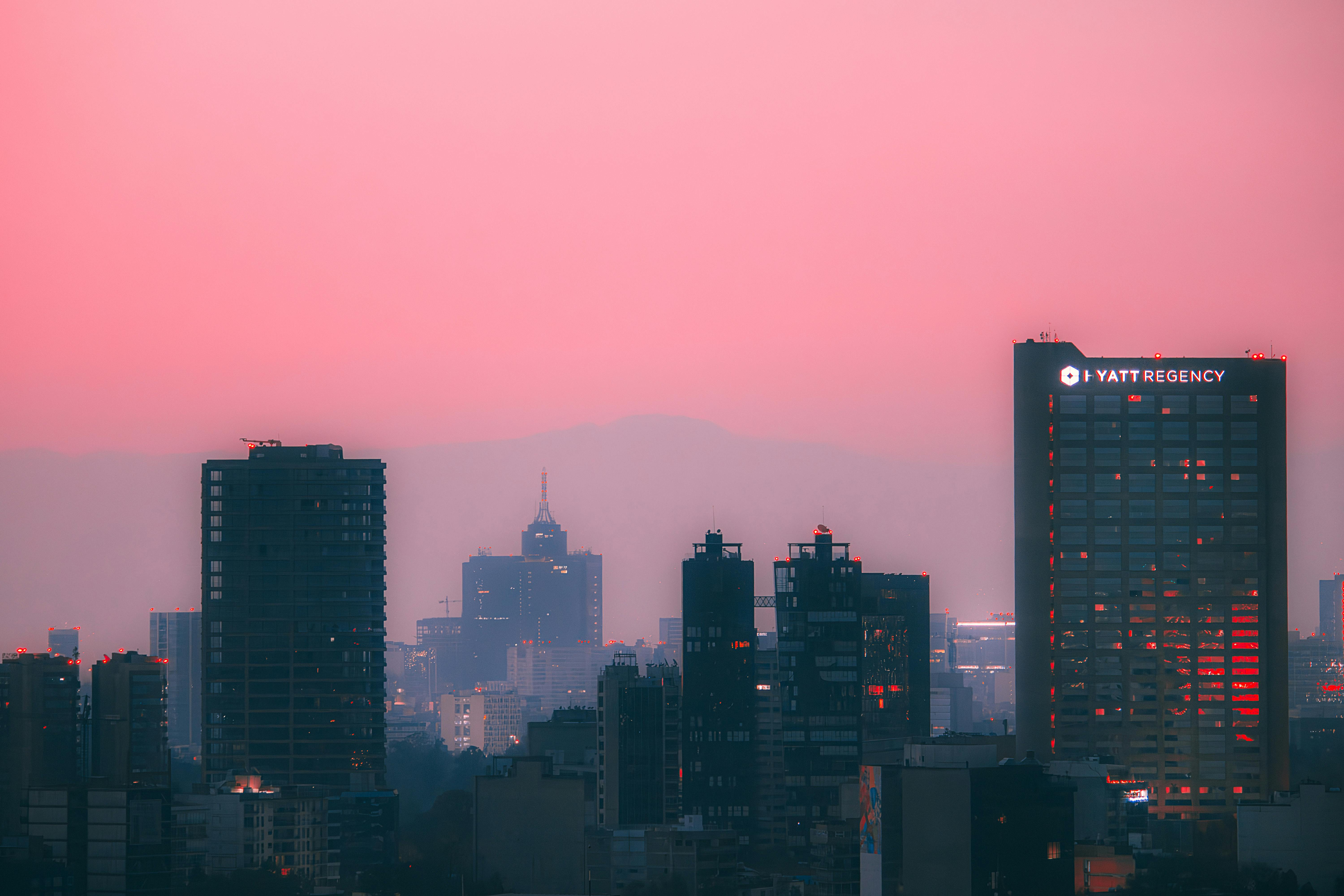 Captivating Mexico City skyline at sunset with vibrant pink sky and modern architecture.