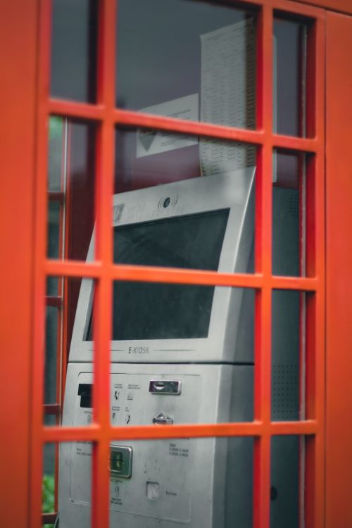 Free A modern ATM inside a classic UK red telephone booth, showcasing contrast between old and new. Stock Photo