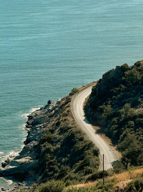 Free A serene coastal road curves along the rugged shoreline in Gazipaşa, Antalya, Türkiye. Stock Photo