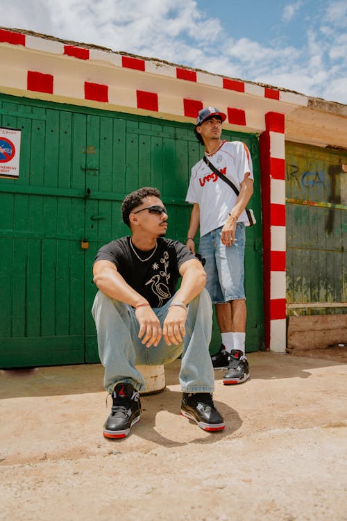 Two men sitting on the ground in front of a green and red building