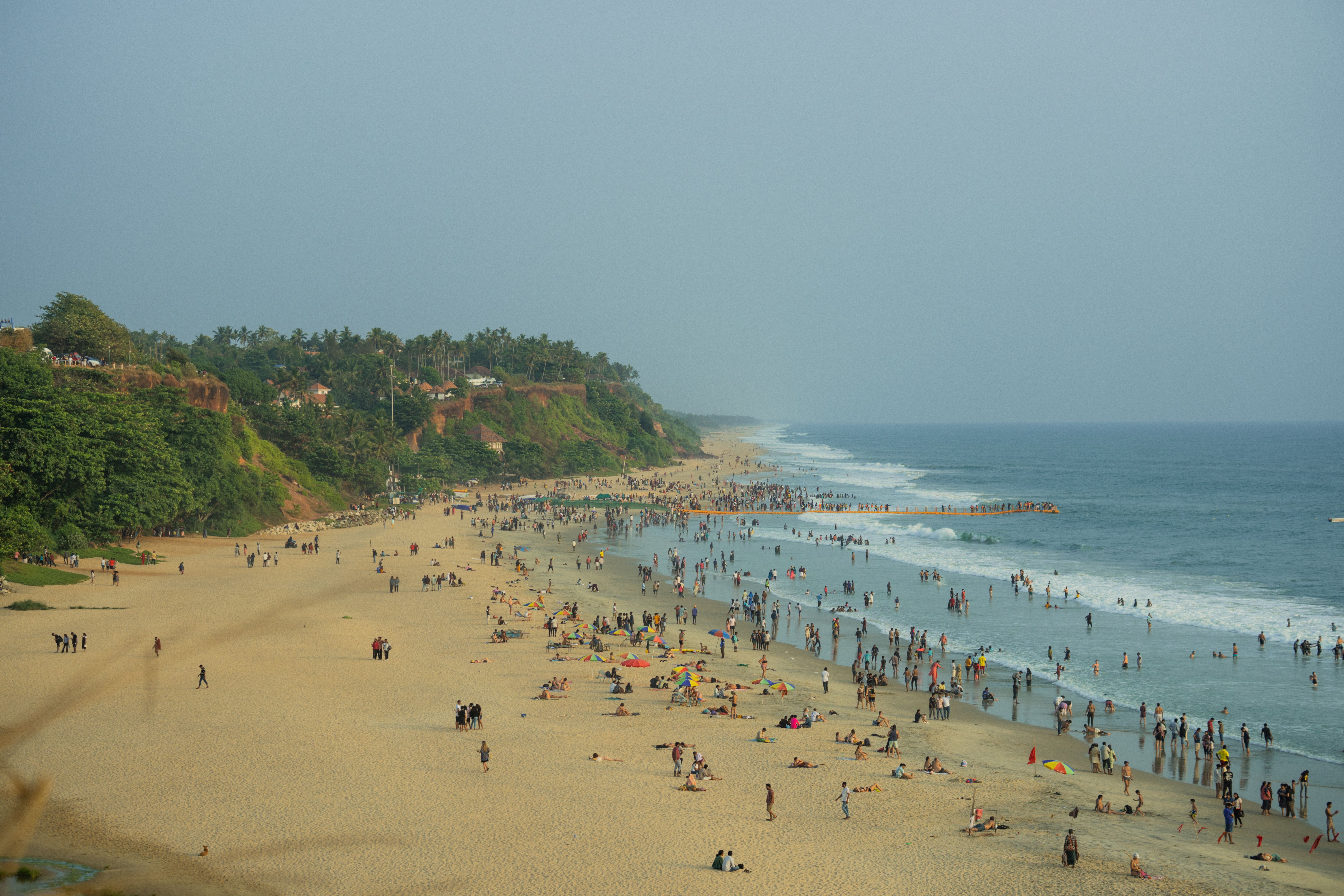 A busy beach with cliffs and waves, capturing summer relaxation and coastal scenery.
