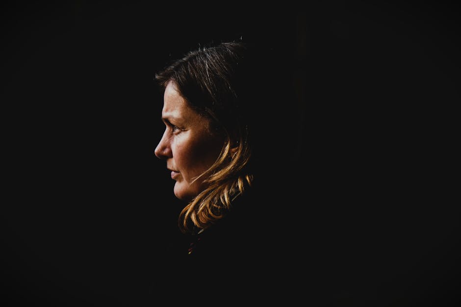 Side profile portrait of a woman with dark background, capturing introspection.