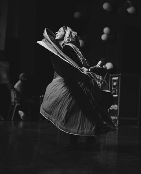 A captivating black and white image of a woman passionately performing a traditional dance in cultural attire.