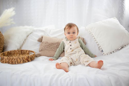 Free Photo of a Little Baby Sitting on a Bed  Stock Photo