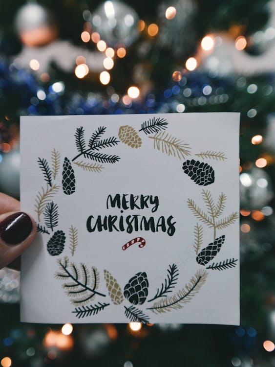 Free Person Holding Beige and Black Floral Merry Christmas Card Stock Photo