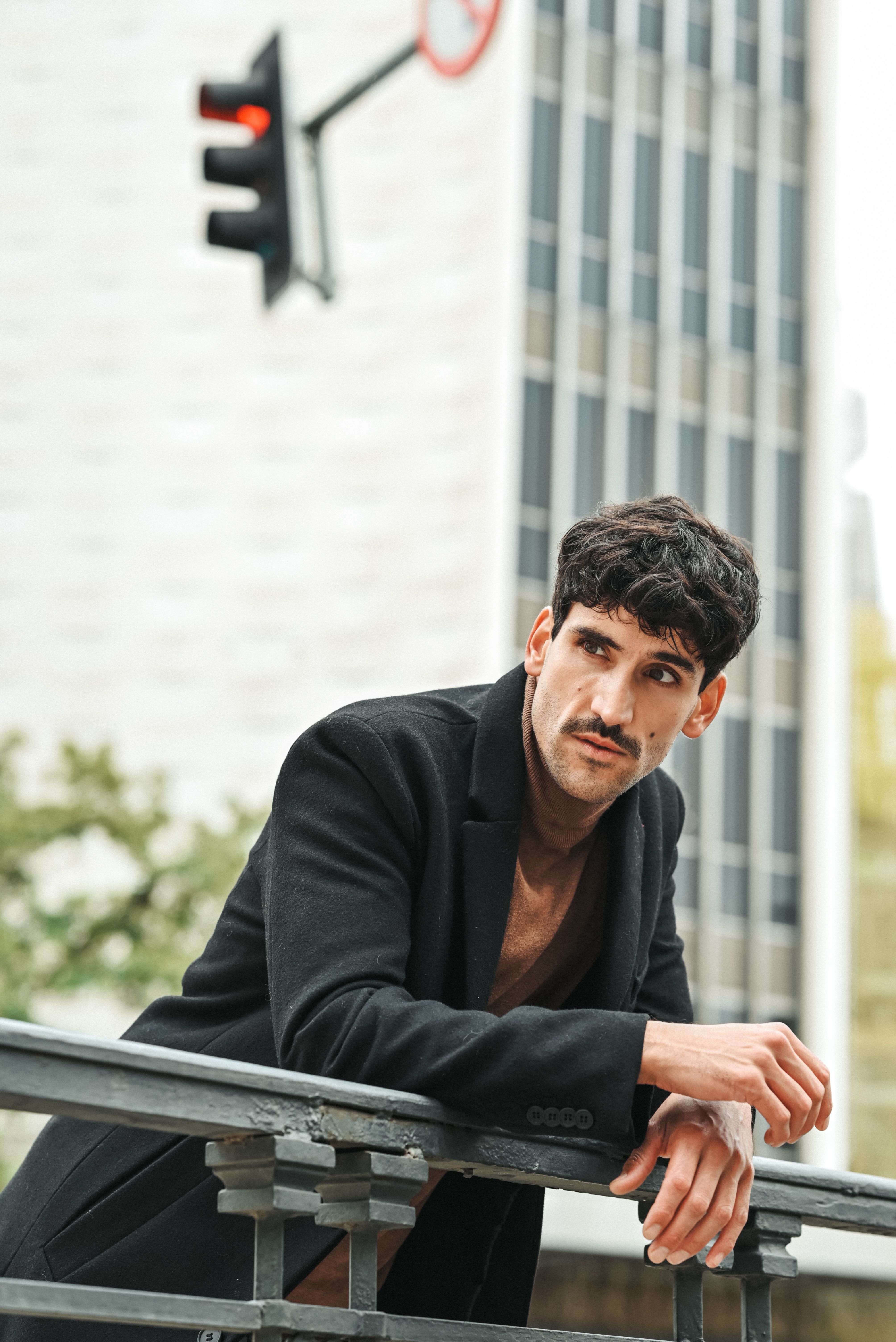 Brunette Man in Black Coat Leaning on Railing · Free Stock Photo