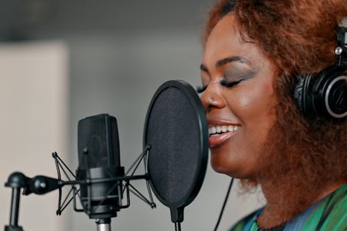 A woman singing into a microphone in a recording studio