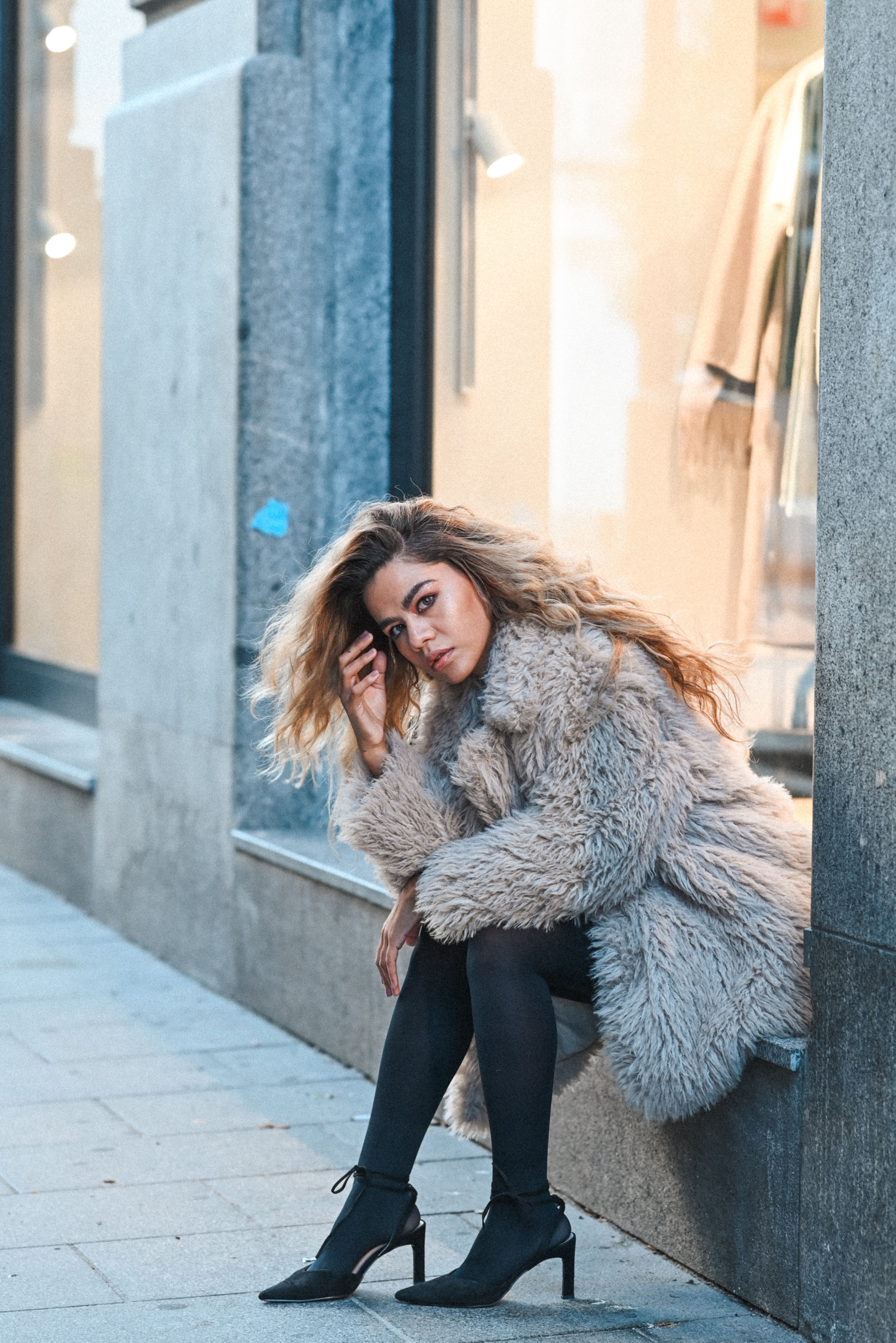 A Woman in a Coat Sitting by the Shop Window · Free Stock Photo