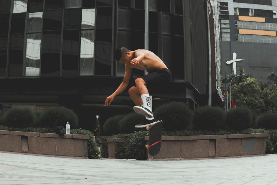 Young male skateboarder executing a trick outdoors in city environment.