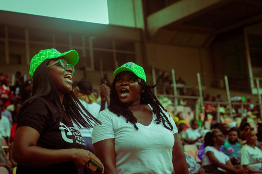 Two women joyfully cheering at a lively outdoor stadium event, showcasing vibrant energy.