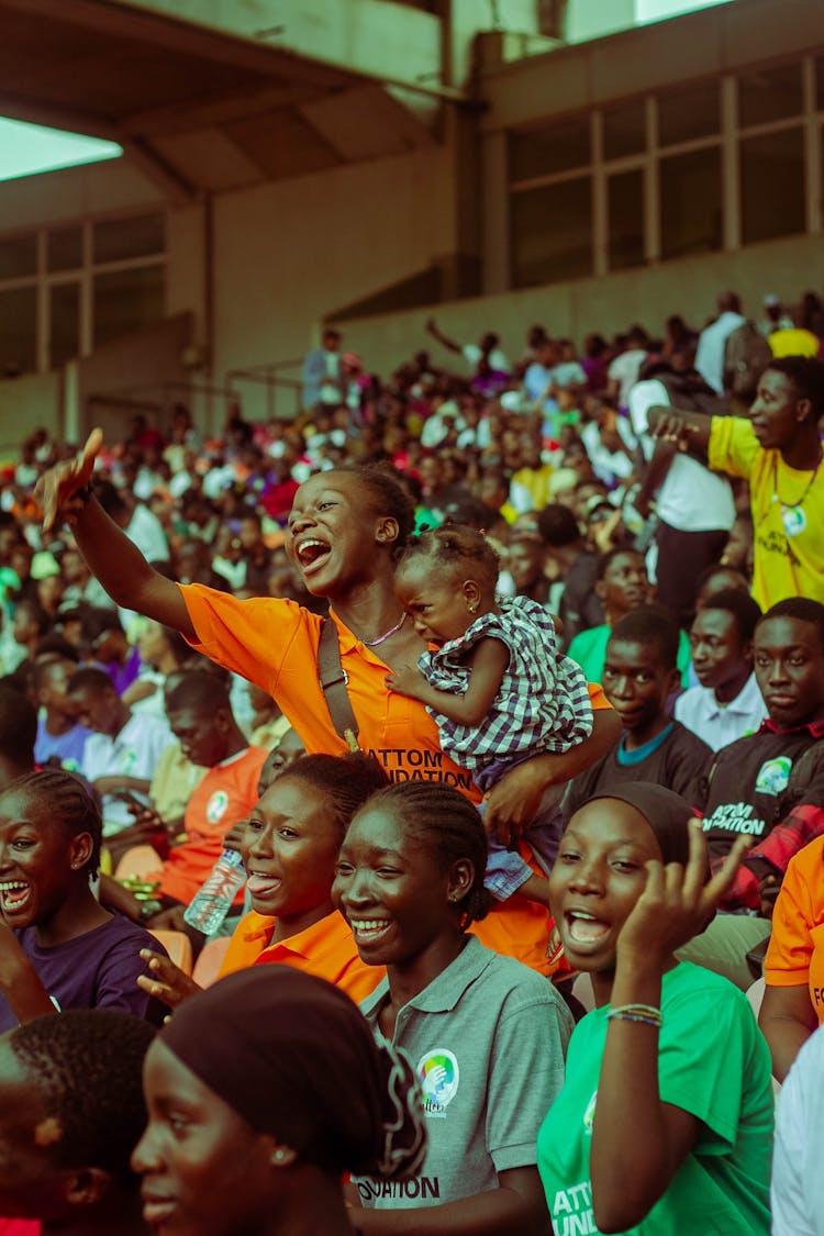 Mother With Baby Standing In Crowd At Stadium