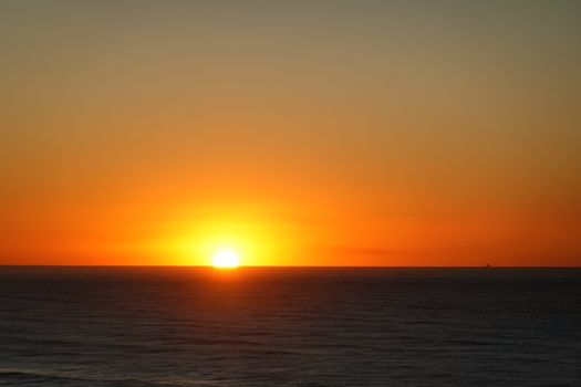 A tranquil ocean sunset with vibrant orange hues reflecting off the water, capturing nature's beauty.
