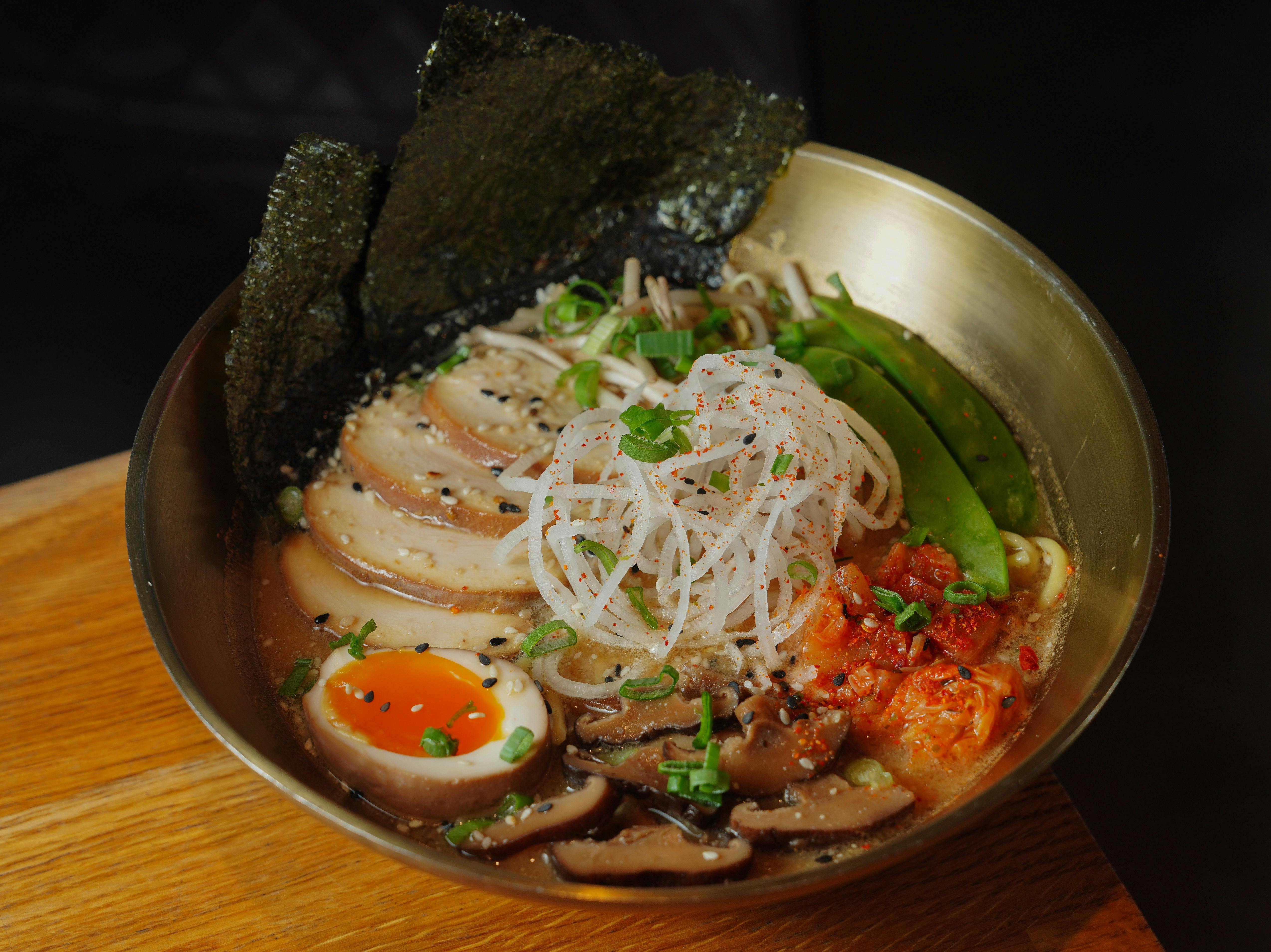 Close-up of a flavorful ramen bowl with egg, nori, and vegetables, perfect for food photography.