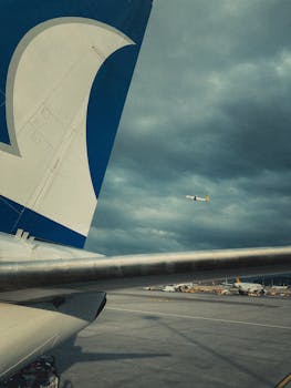 Close-up of airplane tail on tarmac under a dramatic cloudy sky. Aerial view.