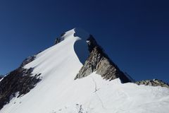 A stunning view of a snow-covered mountain peak under a clear blue sky, capturing the essence of alpine adventure.